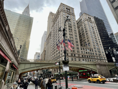 Bustling street in Midtown Manhattan, with the Park Avenue Viaduct near Grand Central Station, surrounded by iconic New York skyscrapers.